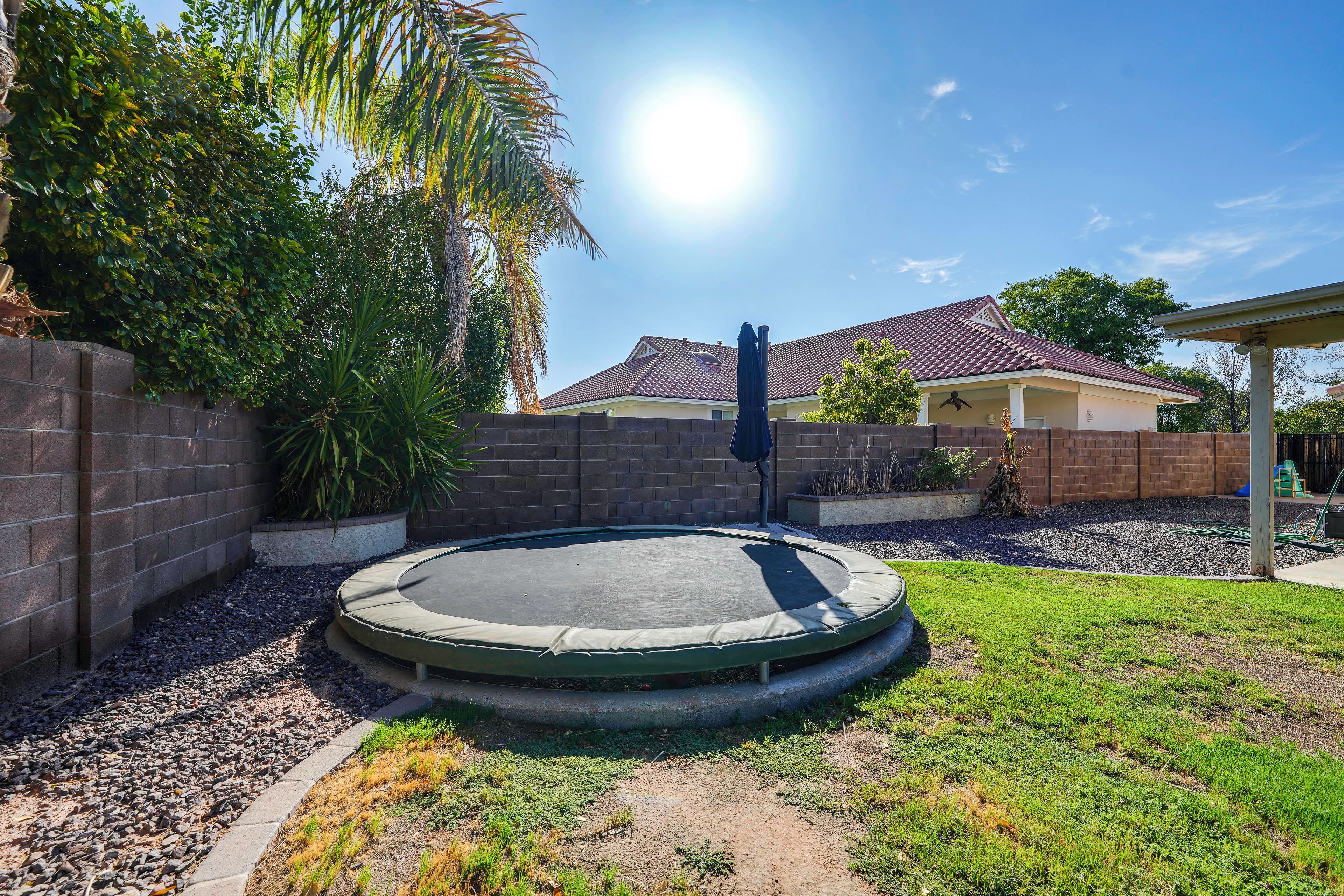 A residential area with a trampoline, a brick wall, and a house with a tiled roof.