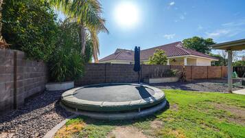 A residential area with a trampoline, a brick wall, and a house with a tiled roof.