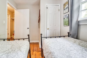 A bedroom with two beds, a door, and a poster on the wall. - 5 Mi to Honky Tonk Hwy! Charming Escape w/ Porch (Nashville)