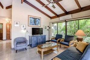 A living room with a television, seating, artwork, and a view of greenery. - Beach Access & Resort Perks: Playa Hermana Villa (Sardinal)