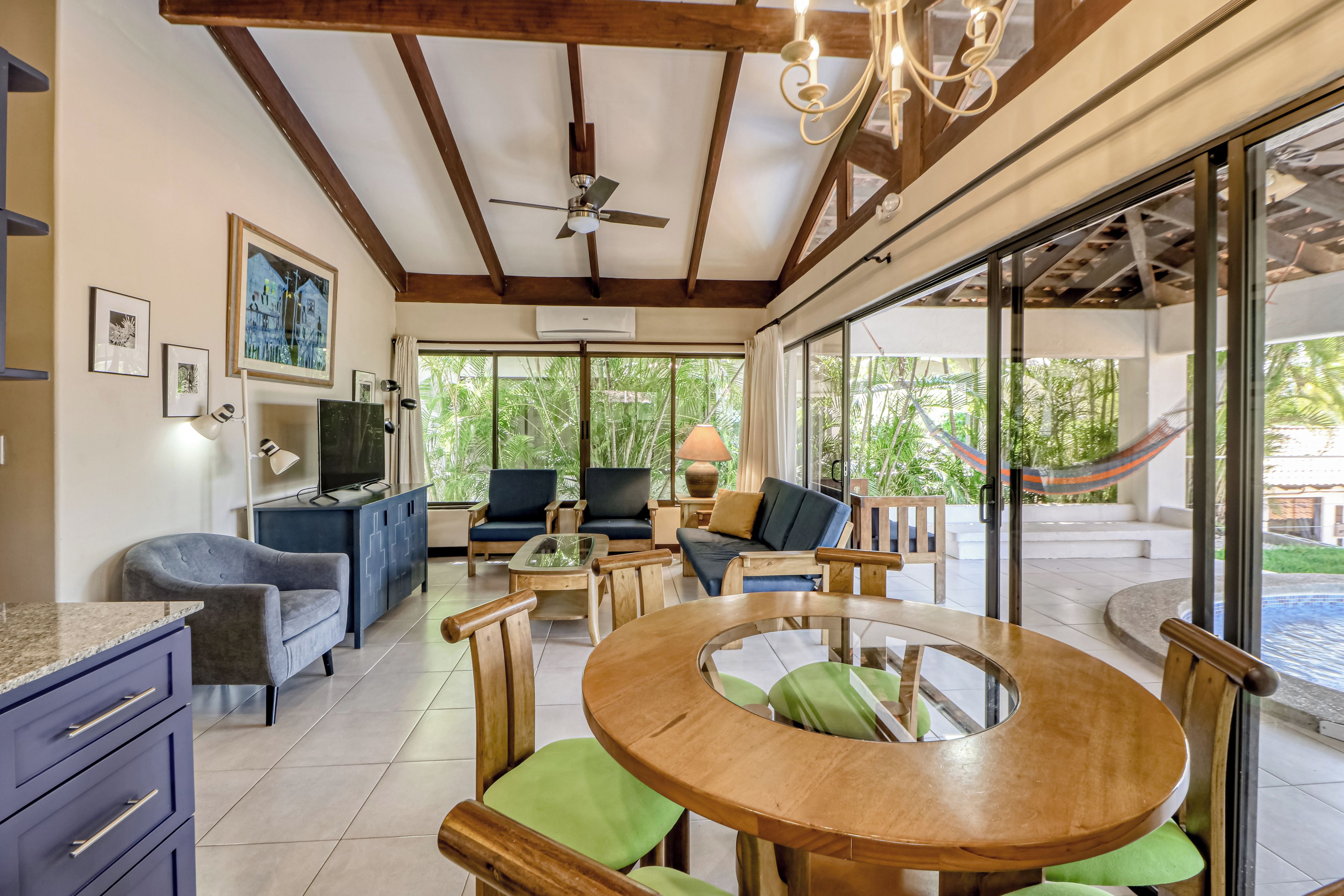 A spacious living area with a ceiling fan, a television, and a dining table with chairs.