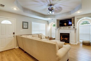 A living room with a beige sectional sofa, a fireplace, and a television mounted above it.