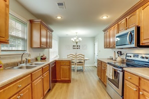 A kitchen with wooden cabinets, a built-in microwave, a sink, and a dining area with a table and chairs.