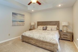 A bedroom with a wooden bed, two bedside tables with lamps, a ceiling fan, and a painting on the wall. - Quiet Jonesboro Home w/ Yard: 3 Mi to ASU (Jonesboro)