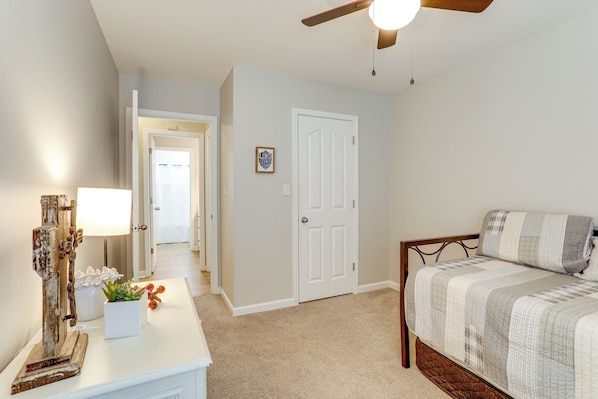 A bedroom with a bed, a nightstand, a lamp, and a ceiling fan.