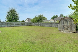 A backyard with a wooden fence, a shed, and houses in the background.