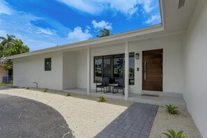 A modern house with a covered porch, a wooden door, and a gravel driveway. - Waterfront Hollywood Oasis w/ Private Pool! (Hollywood)
