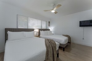 A hotel room with two beds, a ceiling fan, a TV mounted on the wall, and a window with blinds. - Waterfront Hollywood Oasis w/ Private Pool! (Hollywood)