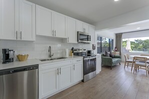 A modern kitchen with white cabinetry, stainless steel appliances, and a view to the outside. - Waterfront Hollywood Oasis w/ Private Pool! (Hollywood)