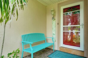 Een turquoise bank voor een gebouw met een deur die een rood glazen paneel en een 'WELCOME' bord heeft.