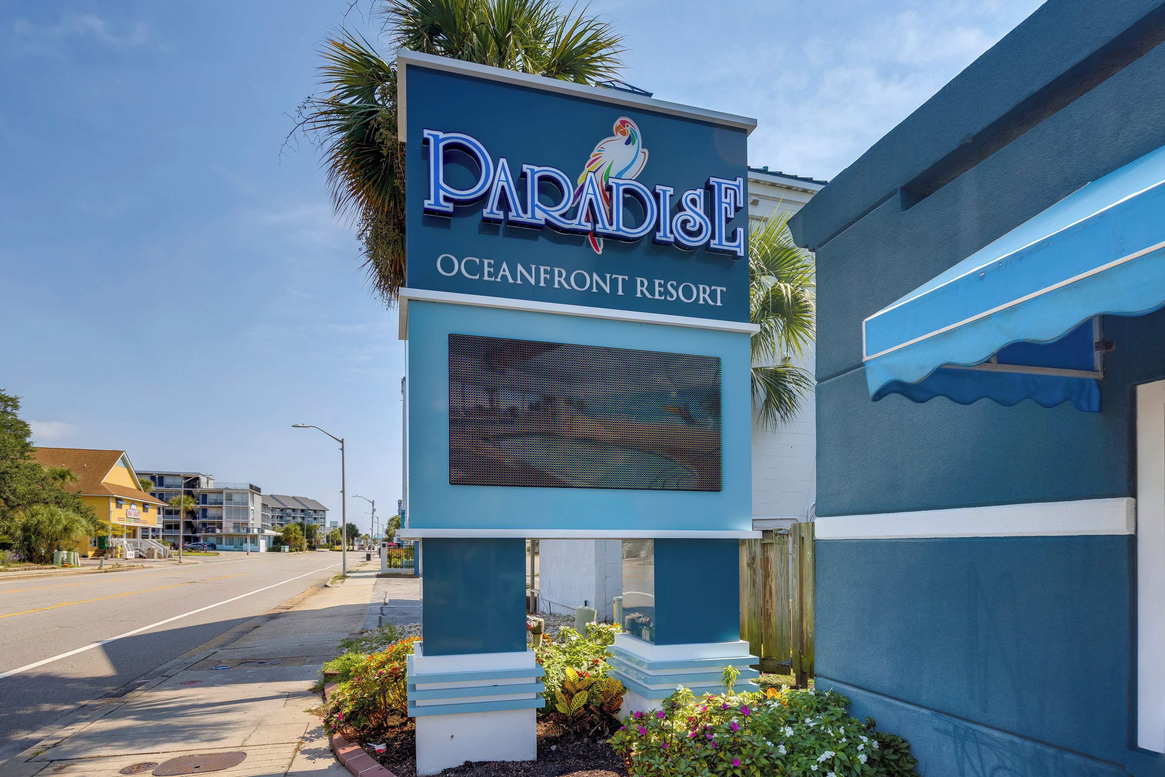 A sign for Paradise Oceanfront Resort with a large digital display.