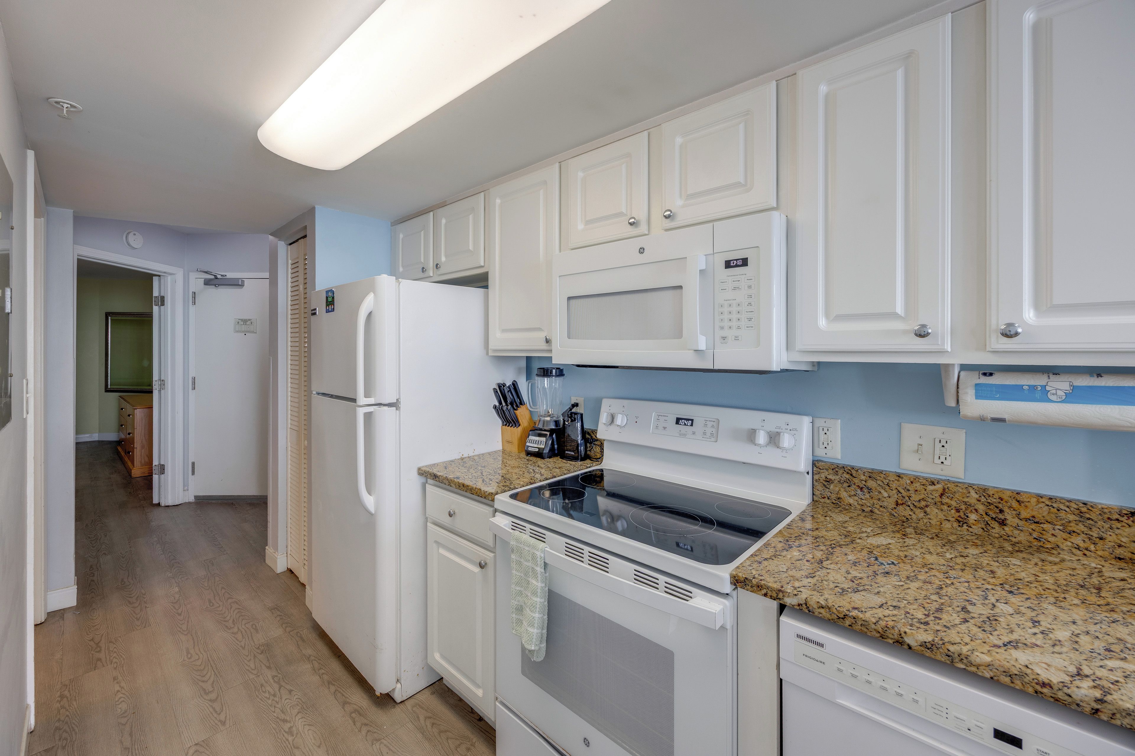 A kitchen with white cabinets, a microwave, a refrigerator, an oven, and a dishwasher.