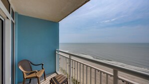 Een balkon met uitzicht op zee, een stoel en een klein tafeltje.