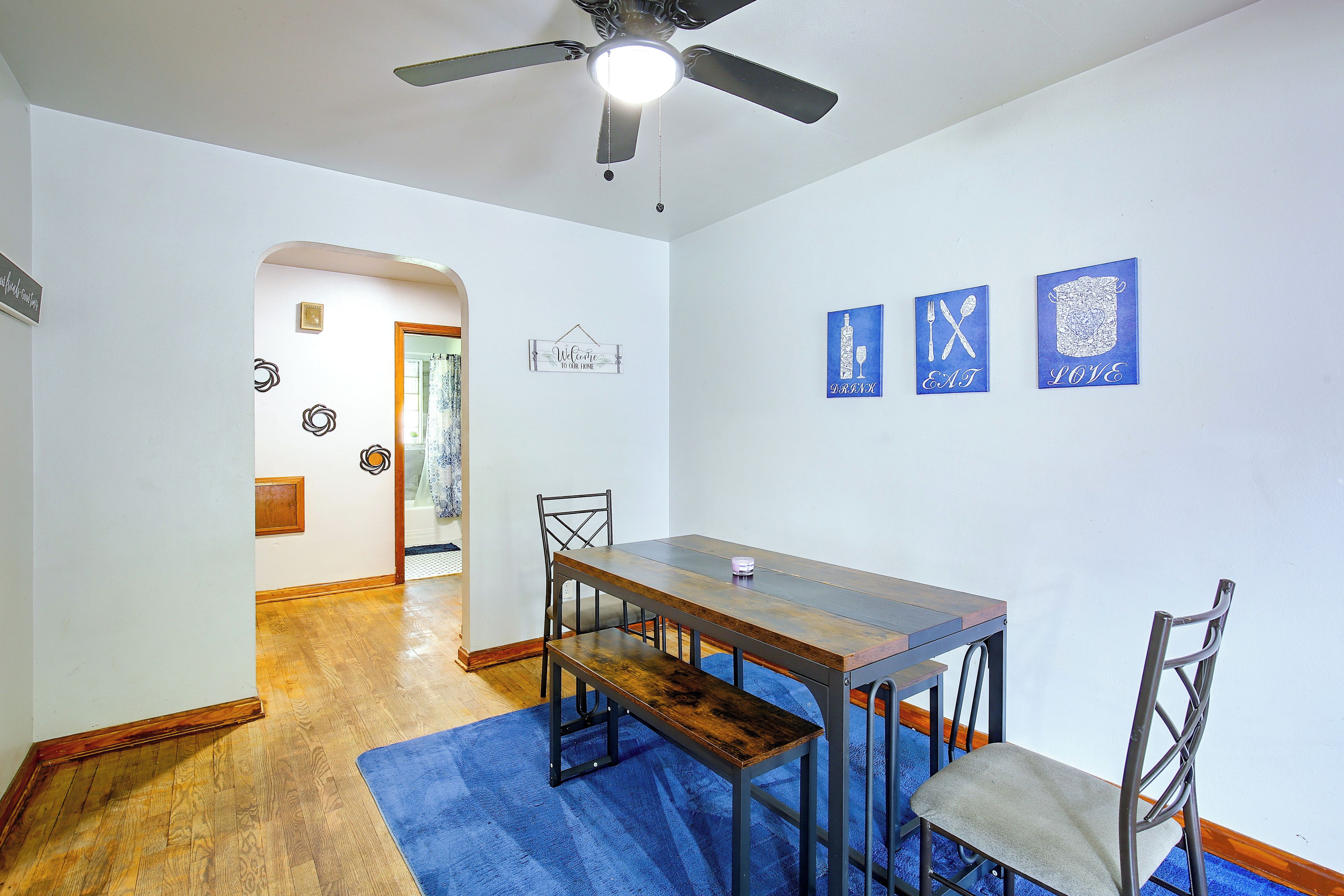 Un espace repas comprenant une table et des chaises, un ventilateur de plafond et des œuvres d’art murales.