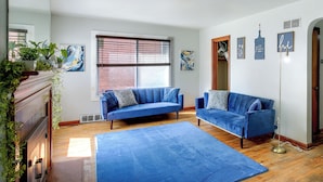 Ein Wohnzimmer mit zwei blauen Sofas, einem großen blauen Teppich und einer Ziegelwand.