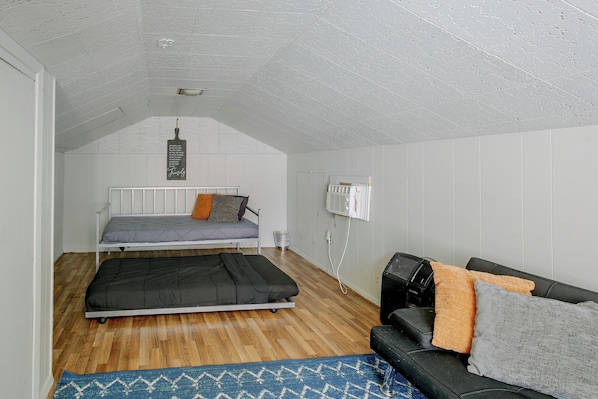 A compact room with two beds, a sofa, a heater, and a wall-mounted air conditioner. - Family Apt 7 Mi to Gateway Arch, Museums & More! (St. Louis)