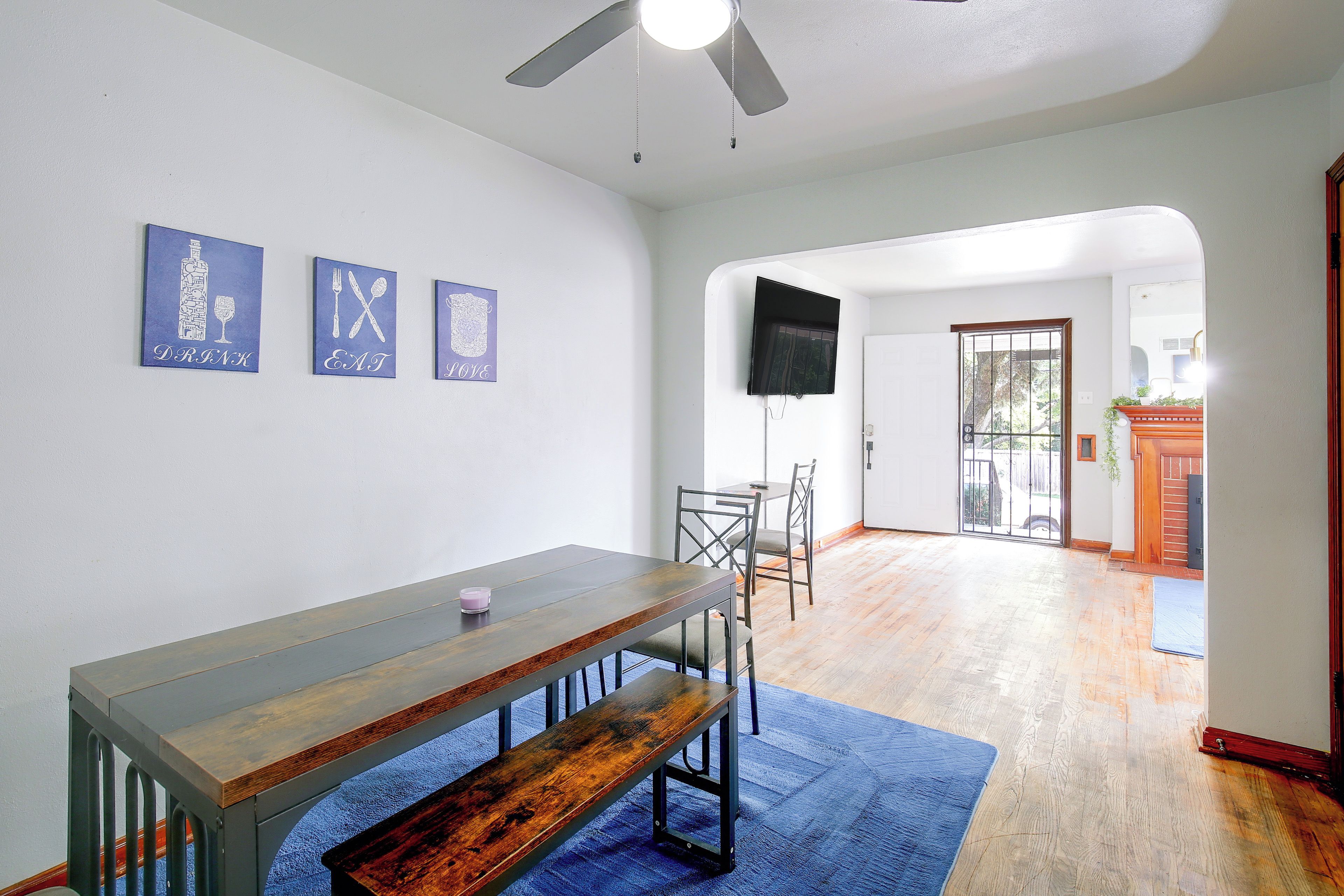 Une pièce comprenant une table à manger, des chaises, un ventilateur de plafond et un tapis bleu.