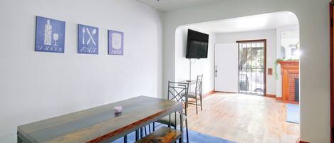 Une pièce comprenant une table à manger, des chaises, un ventilateur de plafond et un tapis bleu.