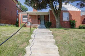 A residential house with a brick exterior, a front porch, and a concrete staircase leading to the front door.