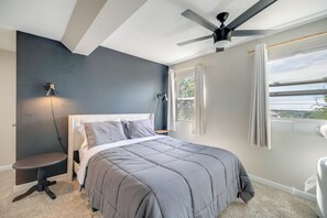 A bedroom with a bed, a ceiling fan, a nightstand, a lamp, and a window with curtains. - Mountain-view Basecamp in Central Colorado Springs (Colorado Springs)