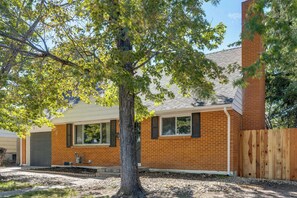 A residential house with a brick exterior, a wooden fence, and a tree in the front yard. - Mountain-view Basecamp in Central Colorado Springs (Colorado Springs)