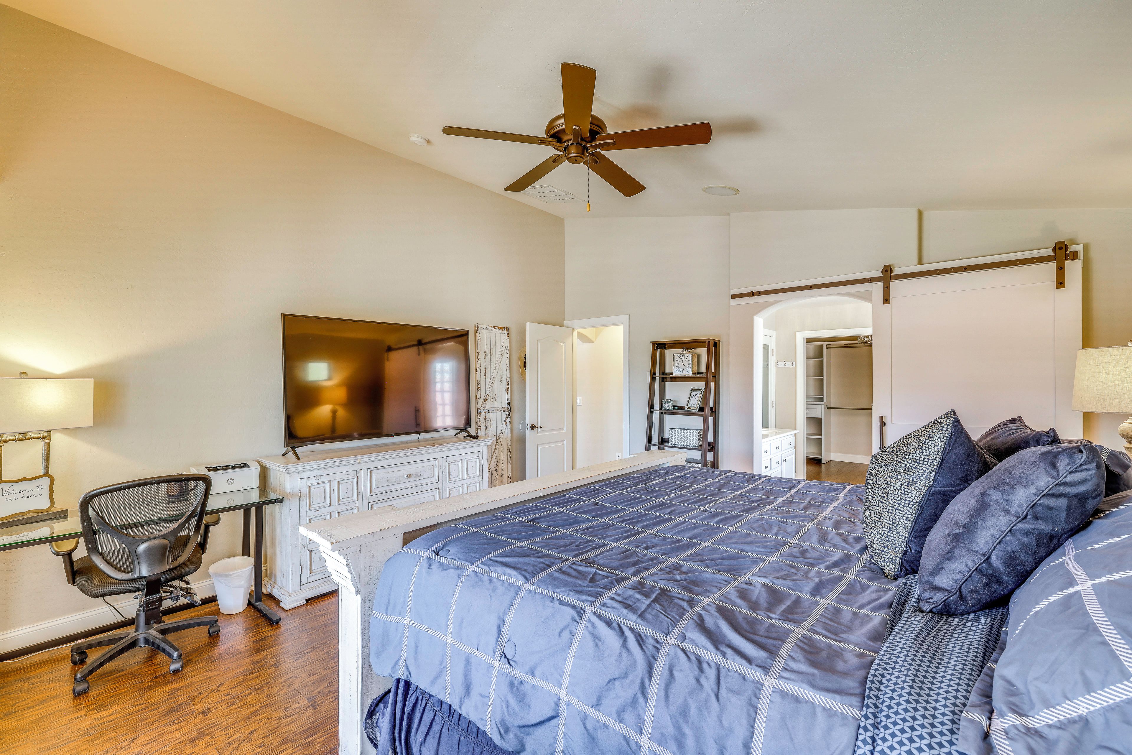 A bedroom with a bed, desk, chair, and a ceiling fan.