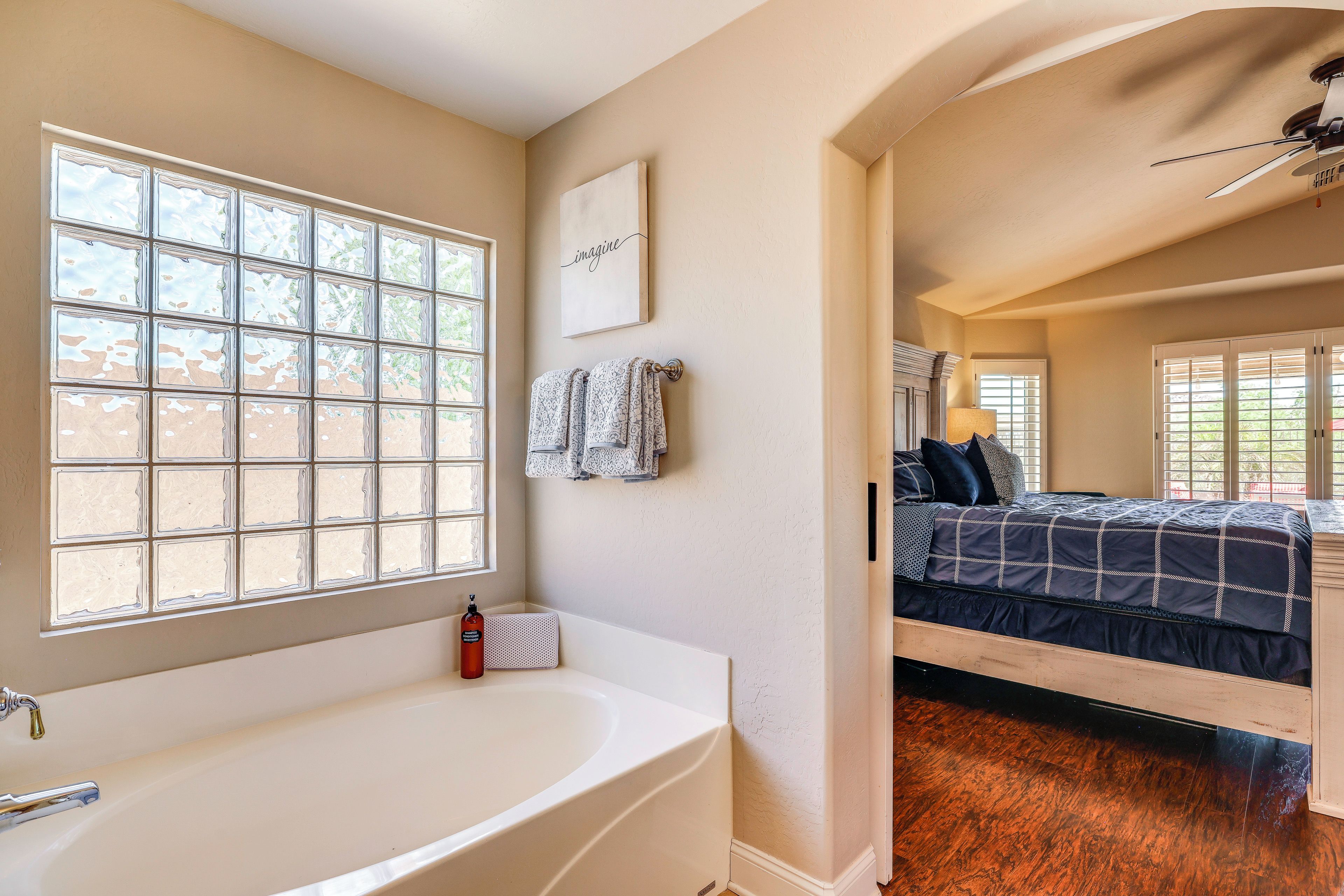 A bedroom with a large window, a bed, and a ceiling fan.