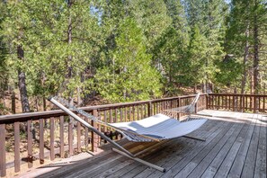 A hammock on a wooden deck surrounded by trees. - Calaveras Adventure Lodge in Blue Lake Springs (Arnold)