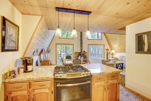 A kitchen with a central island, a stove, and an oven. There are wooden cabinets and a countertop.