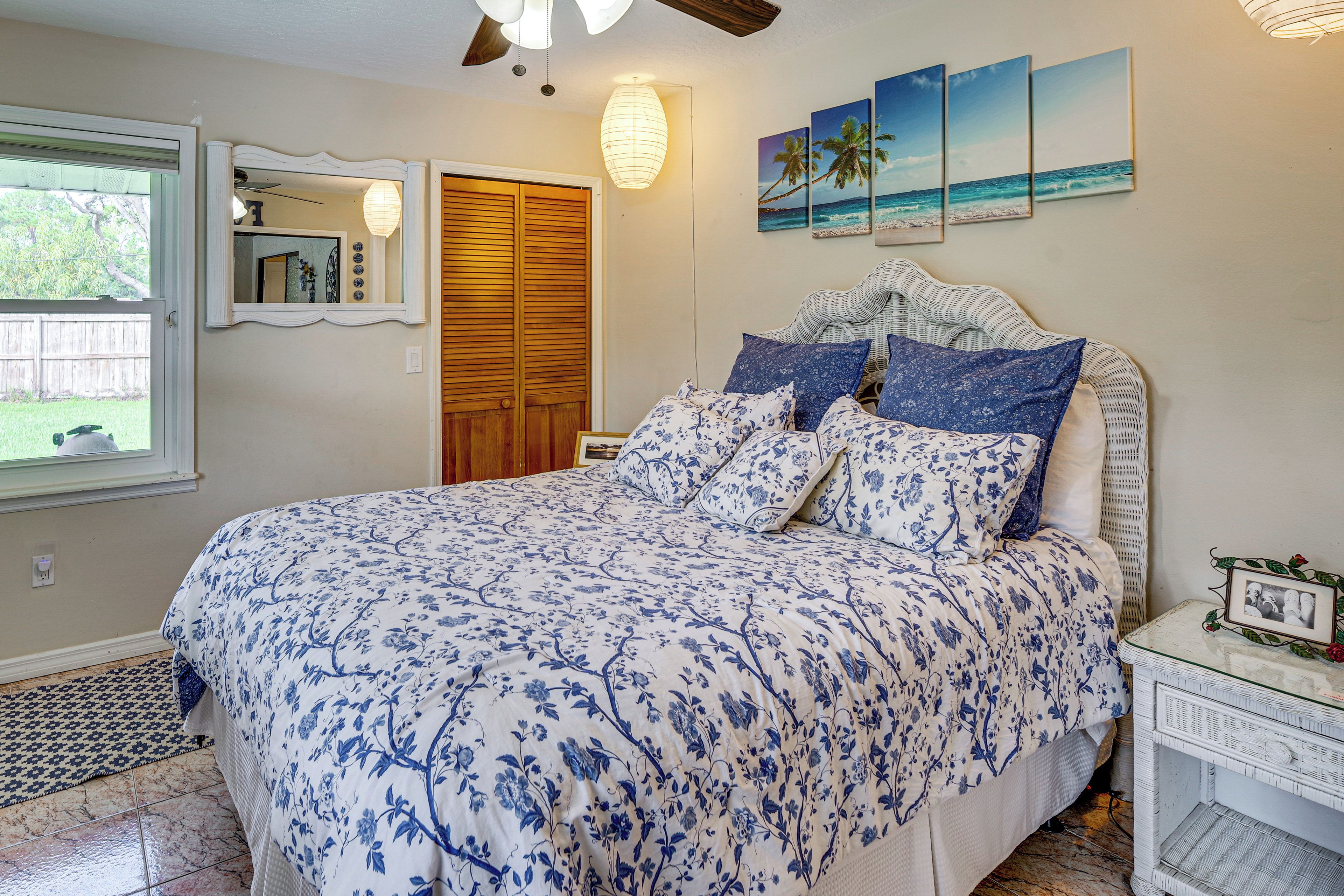 Un dormitorio con cama, mesita de noche, espejo, puerta de madera y decoración en la pared.