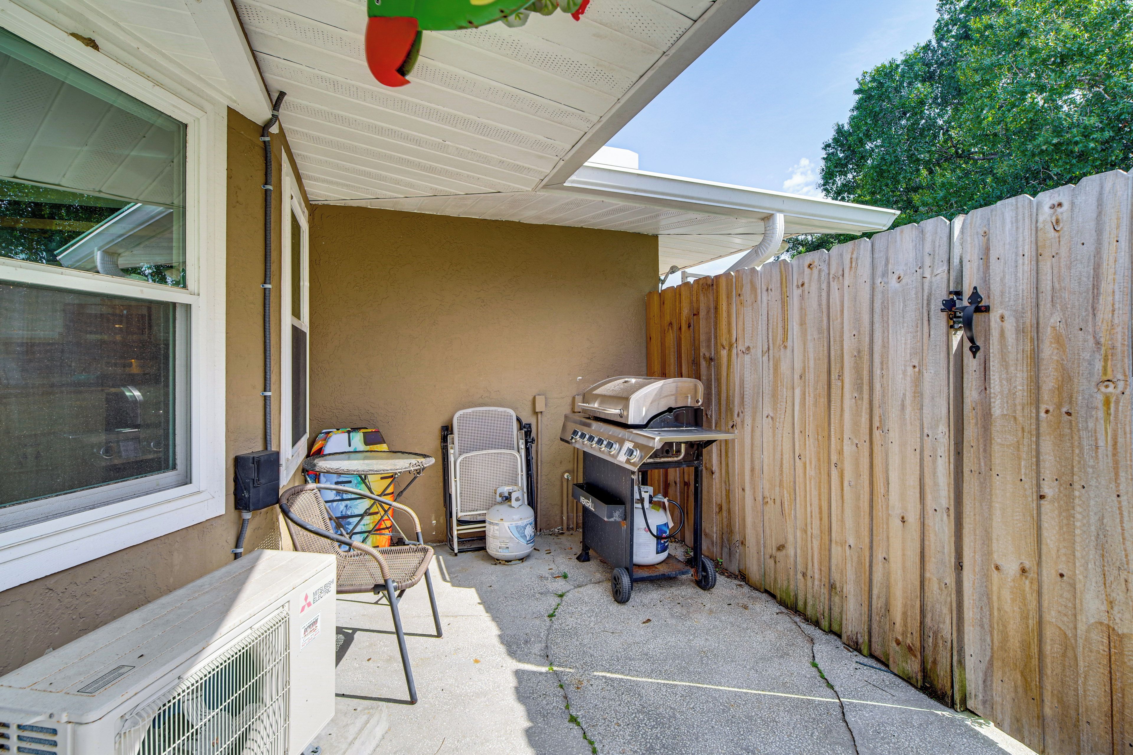 A backyard with a barbecue grill, a chair, a table, and a portable heater.