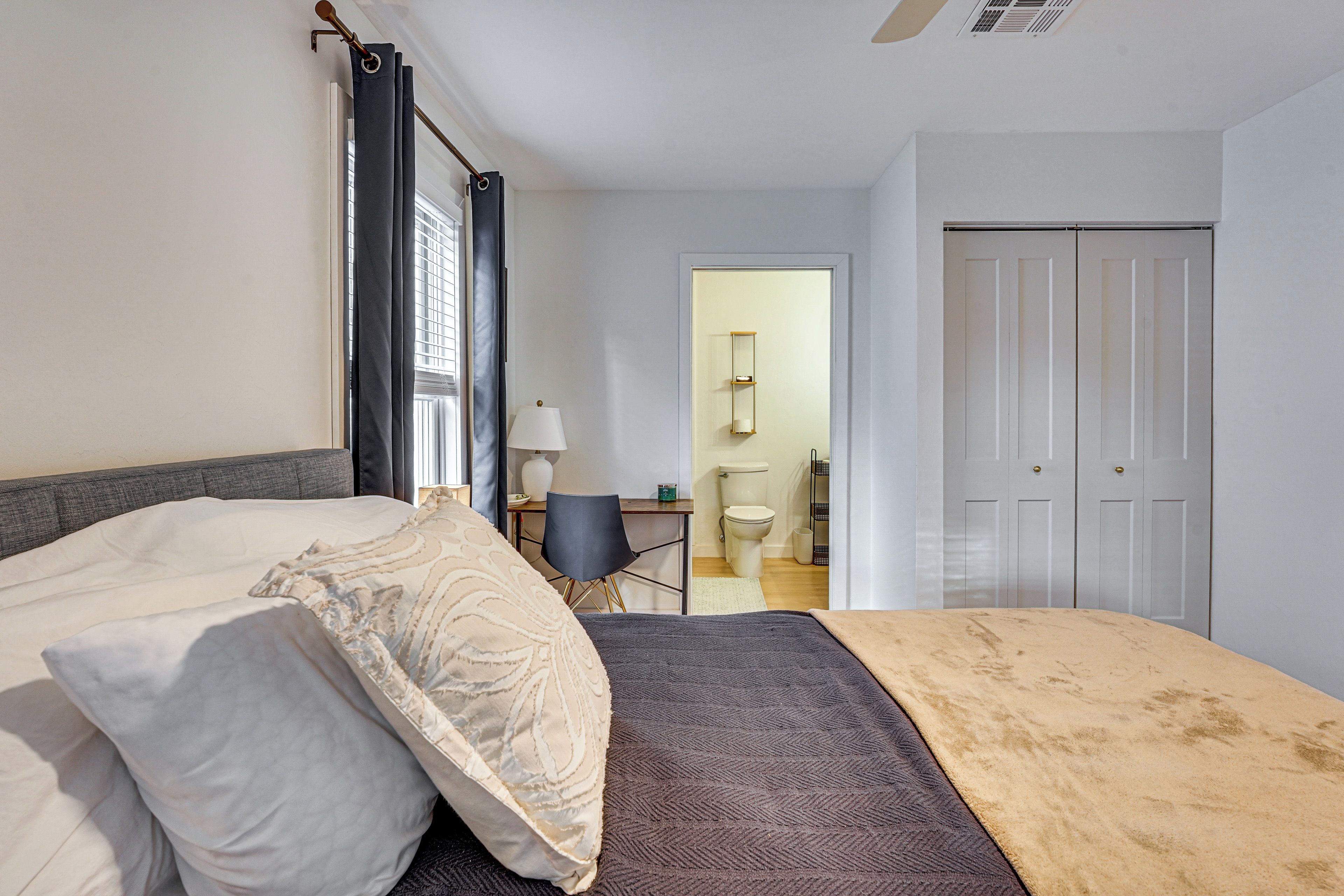 A bedroom with a bed, a bedside table, a lamp, and a wardrobe.