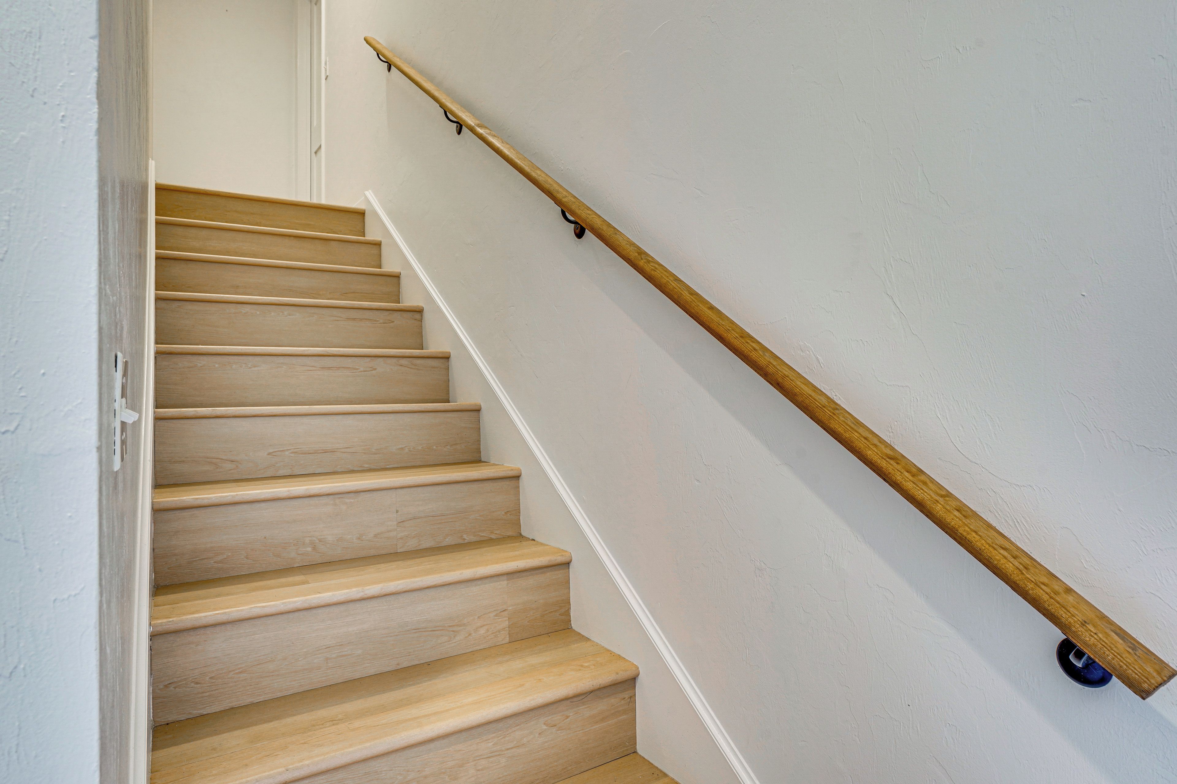 Una escalera de madera con barandilla y un objeto azul en la parte inferior.