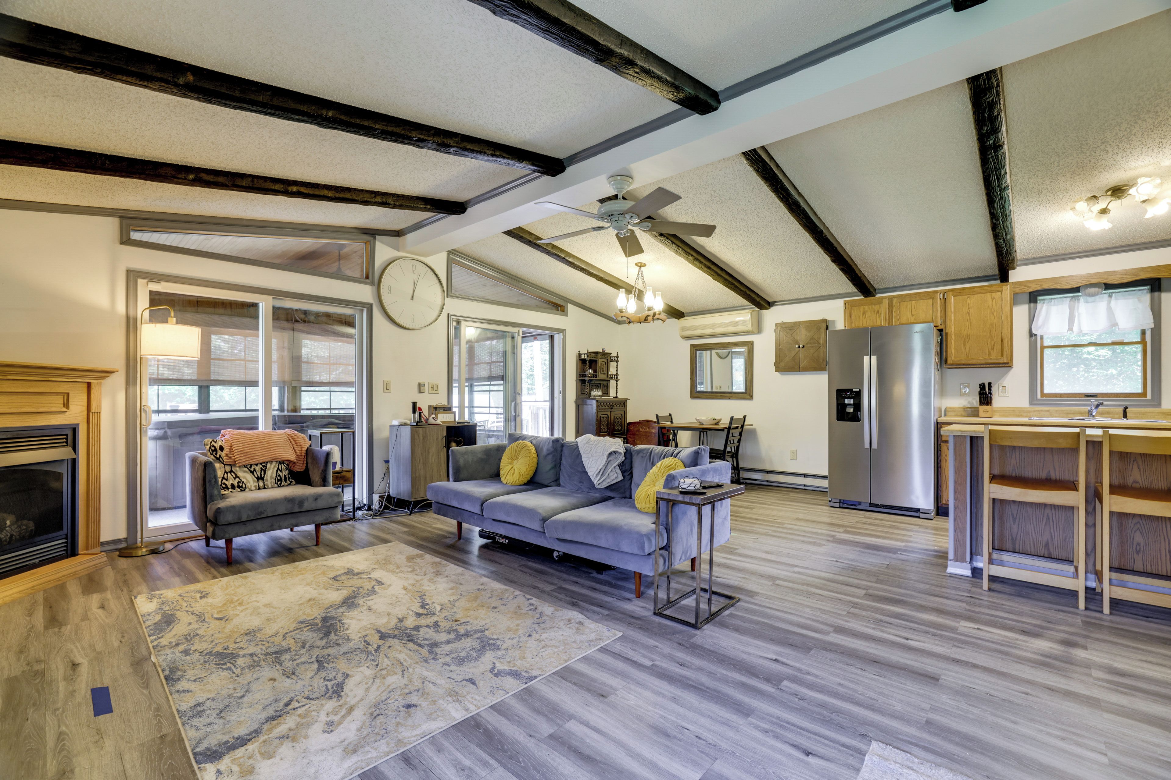 A spacious living area with a fireplace, a sofa, a dining table, and a kitchen with a refrigerator.