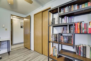 A hallway with a wooden door, a bookshelf filled with books, and a table with a chair. - Deck, Public Lake Access, Mountain Getaway (Equinunk)