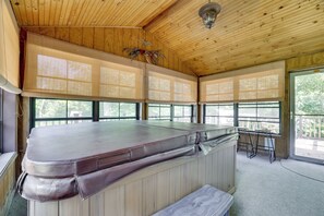 A room with a large wooden ceiling, a bench, and a view through the windows.