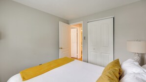A hotel room with a bed, a bedside lamp, and a door leading to another room. - Charming Family Home 11 Mi to Dtwn Richmond! (Chesterfield)