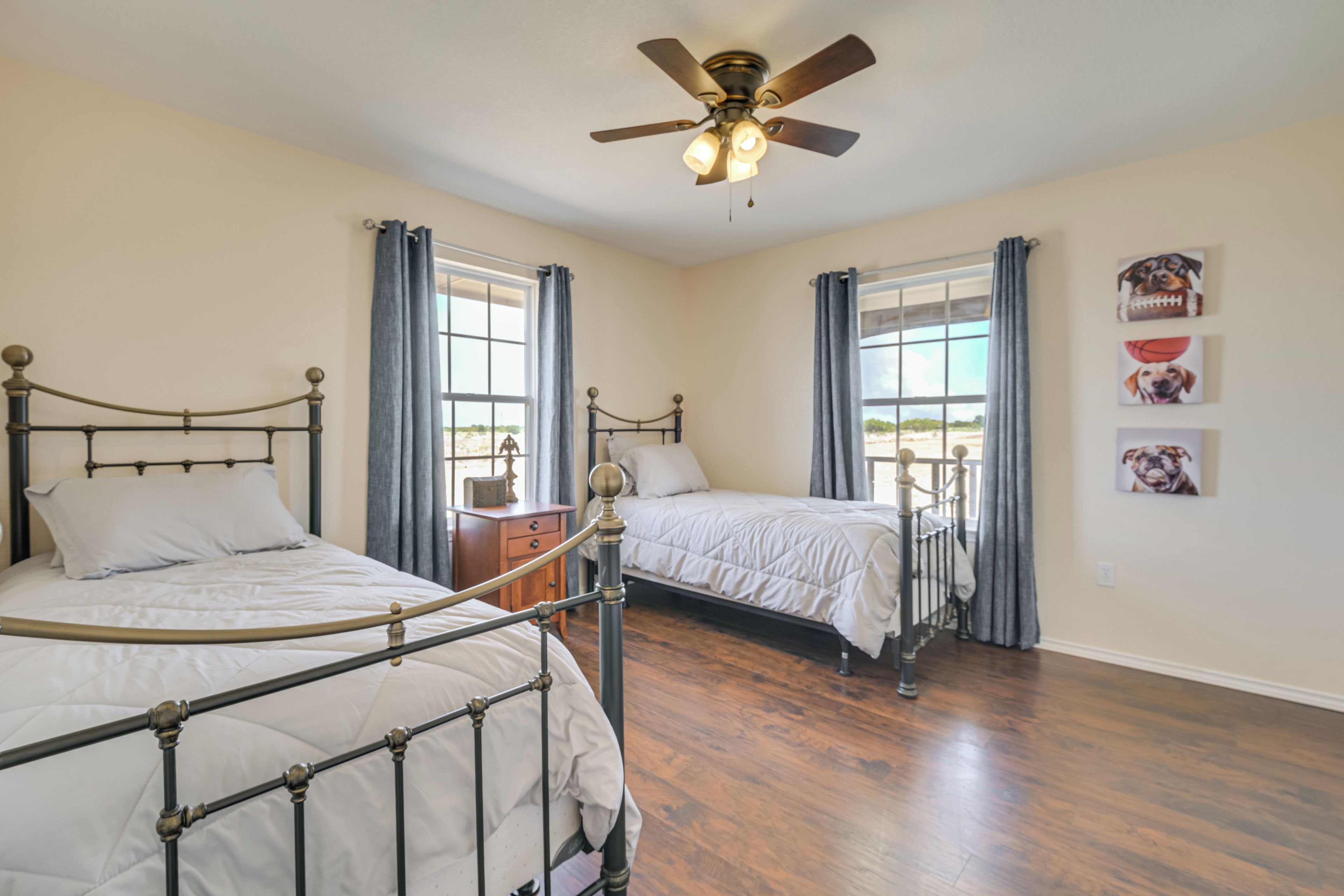 A bedroom with two beds, a ceiling fan, and a window with curtains.