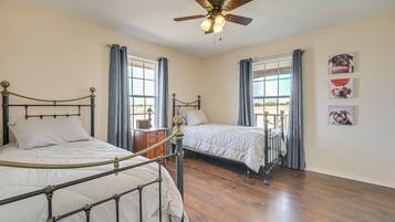A bedroom with two beds, a ceiling fan, and a window with curtains.