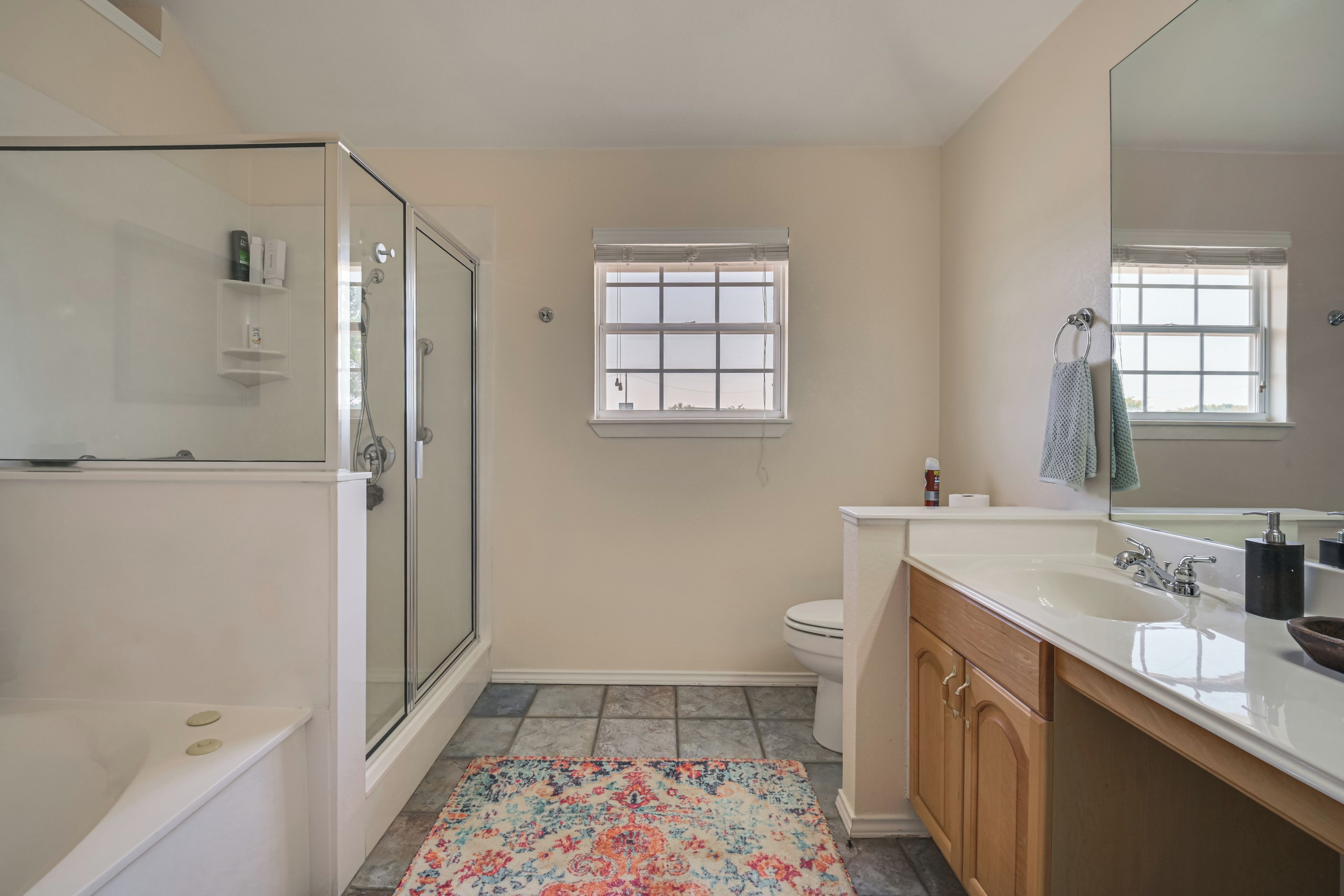 A bathroom with a shower, toilet, sink, and a window.