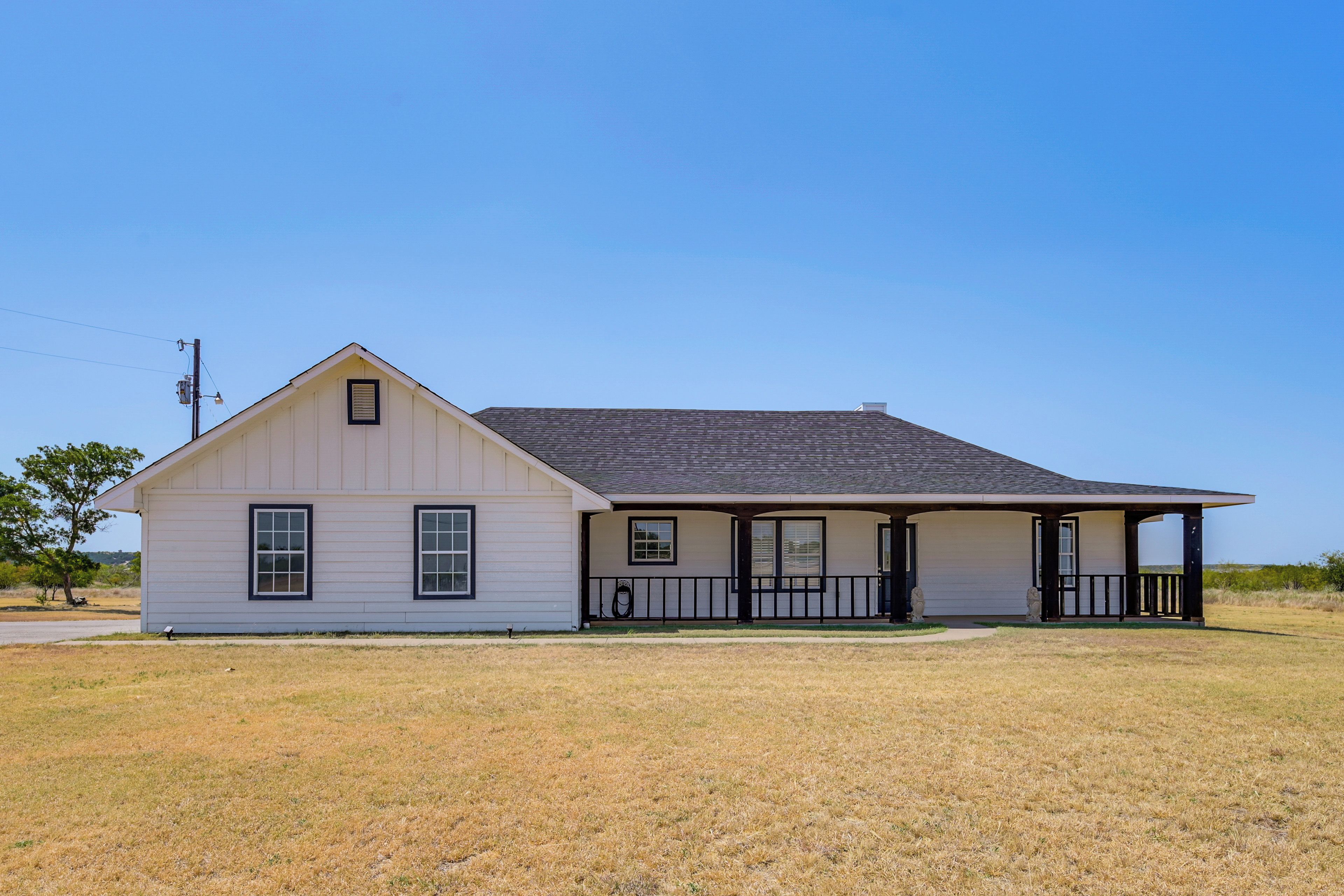 A single-story house with a gabled roof, a front porch with a railing, and a small front yard.