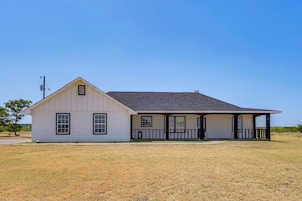A single-story house with a gabled roof, a front porch with a railing, and a small front yard.