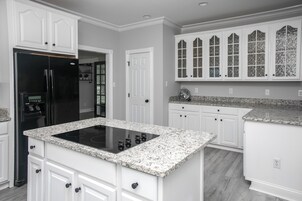 Una cocina moderna con armarios blancos, un refrigerador negro y una encimera de granito.