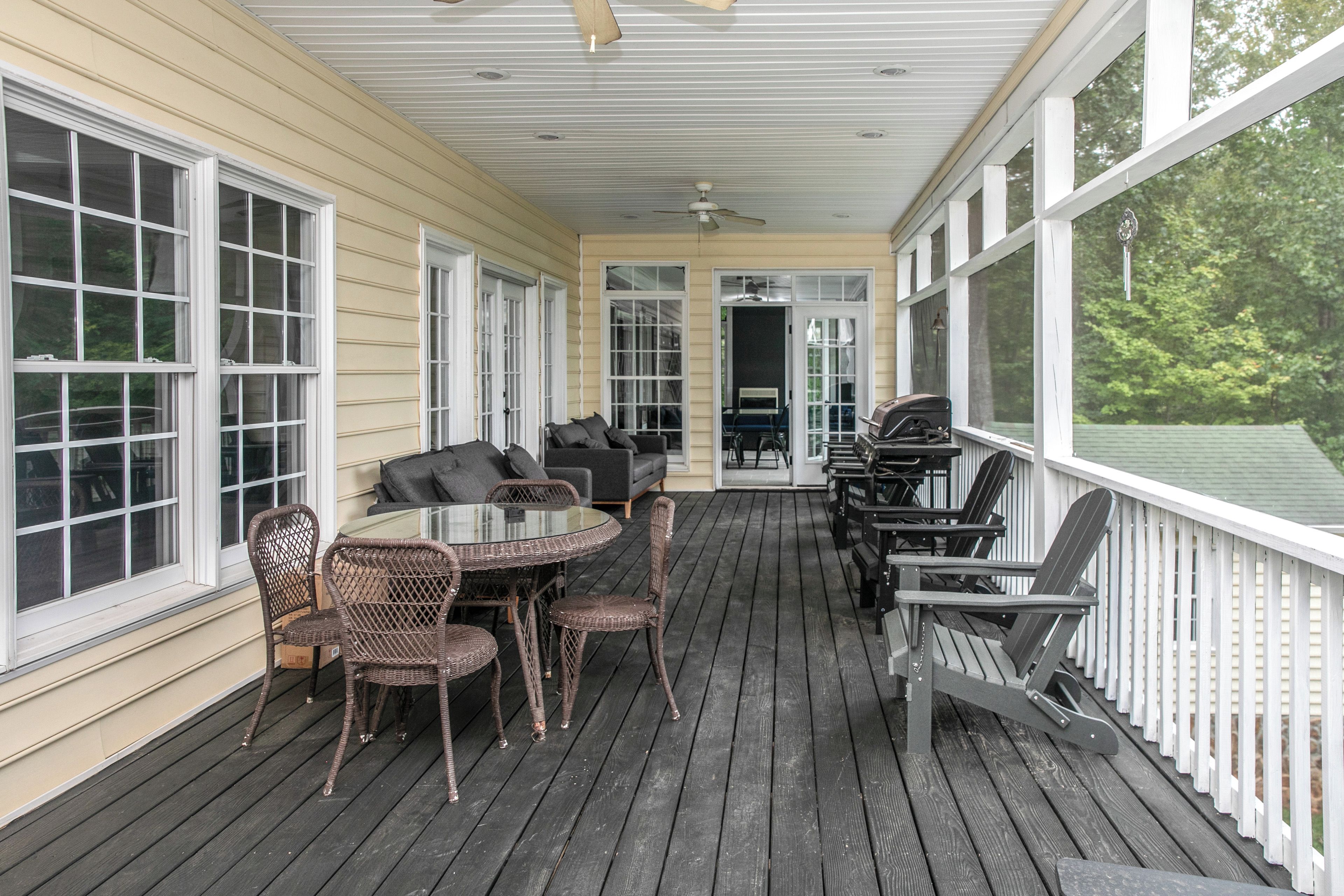 A covered porch with a table and chairs, a ceiling fan, and a view of the outdoors.