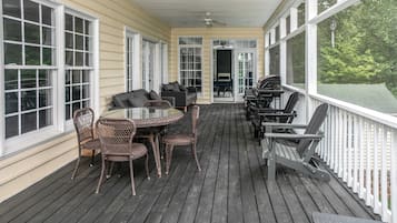 A covered porch with a table and chairs, a ceiling fan, and a view of the outdoors.