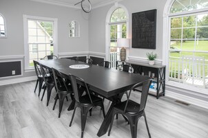 A dining area with a long table, chairs, and a view of the outdoors.