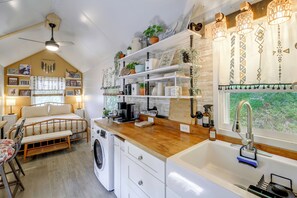 A compact kitchen with a washing machine, a coffee station, and a sink.