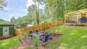A backyard with a wooden deck, a covered seating area, and a barbecue grill.