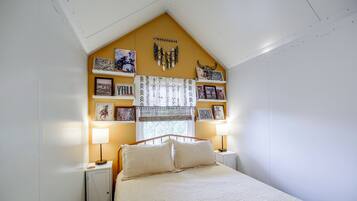 A bedroom with a bed, bedside lamps, a window with curtains, and wall decorations.