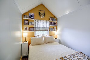 A bedroom with a bed, bedside lamps, a window with curtains, and wall decorations.